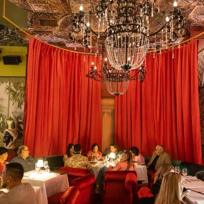 People sitting at a table having dinner, curtains in the back and chandeliers on top.