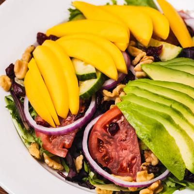 Mango salad with tomato, avocado and walnuts, close-up.