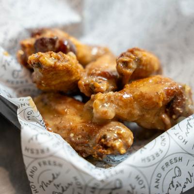 Glossy, sauced fried chicken pieces piled in a paper-lined tray..