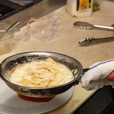 Hands preparing a pasta dish in the kitchen