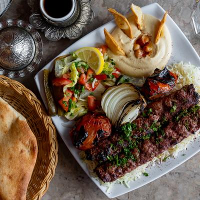 Lamb and beef kebab served with rice, salad, hummus and pita on the side.