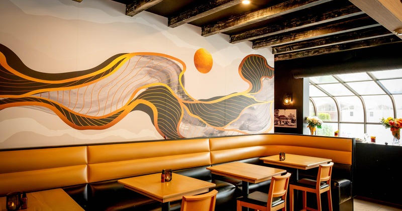 Interior, dining area, banquette bench with tables and chairs, colorful abstract mural on the wall