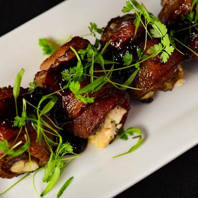 Bacon wrapped stuffed dates topped with micro greens, close up.