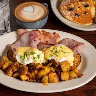 Egg Benedict with smoked ham and  home fries, cup of latte, buttermilk pancakes.