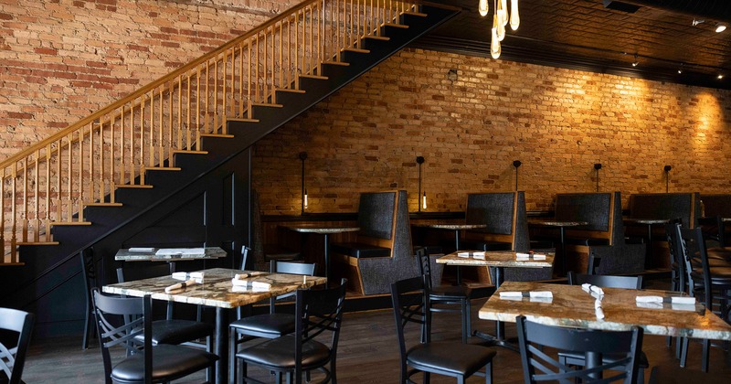 Restaurant interior, dining area with set tables, stairs for the upstairs area