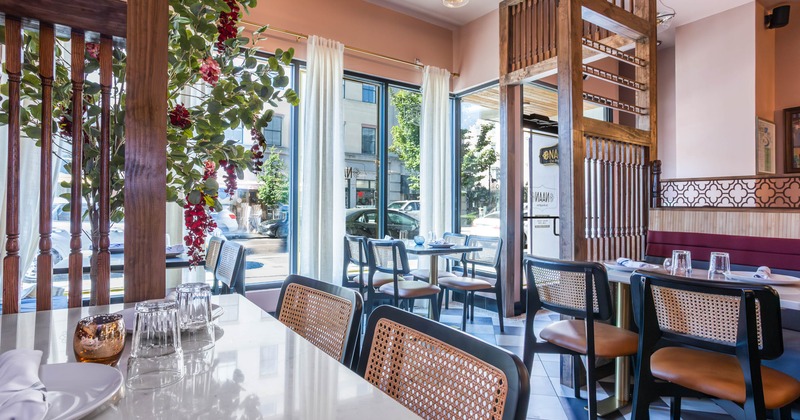 A modern interior - marble-topped tables, rattan-backed chairs, large windows and natural light