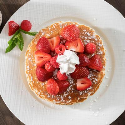 Buttermilk Pancakes topped with strawberries and whipped cream.