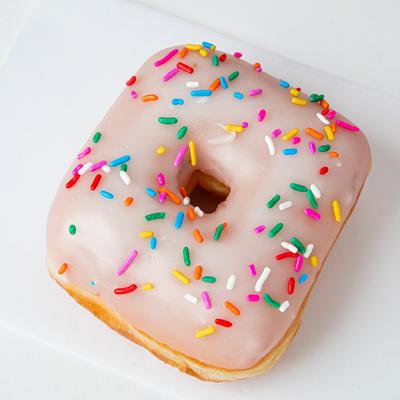 A square donut with vanilla icing and colorful sprinkles.