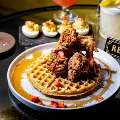 Chicken and waffles grizzled with syrup and garnished with sliced strawberries.