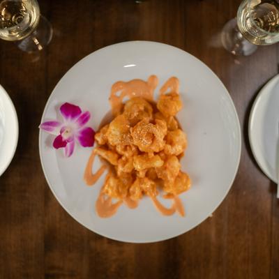 Rock shrimp with creamy sauce and orchid garnish.