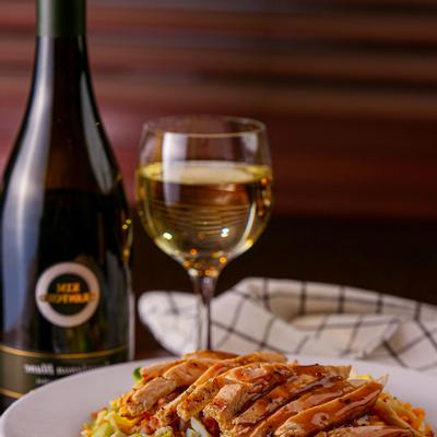 Grilled chicken, veggies and cheese served, accompanied by a glass of white wine