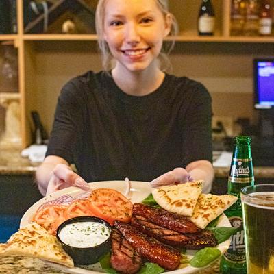 Employee displaying the Loukaniko dish
