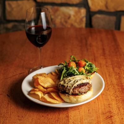 Cafe Wagyu Burger served with chips and a salad, alongside red wine