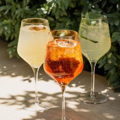 Three different cocktails in tall wine glasses.