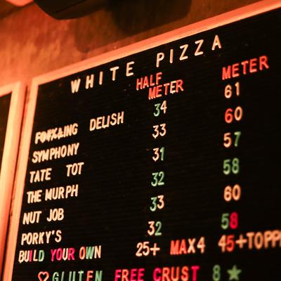 A menu board displaying various white pizza options with names and prices.