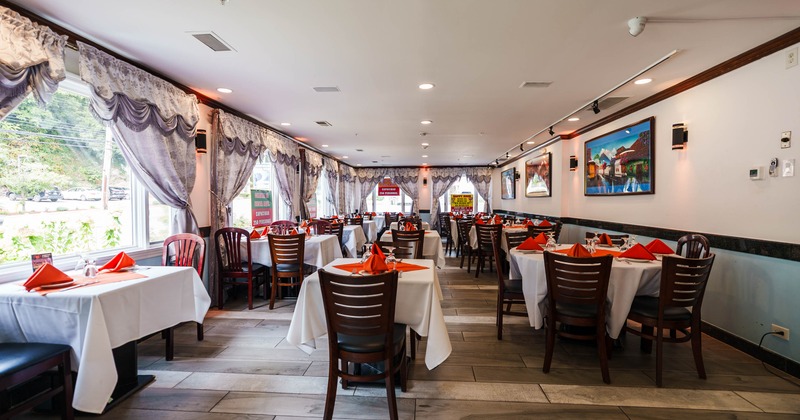 Interior seating area with chairs and tables with tablecloths