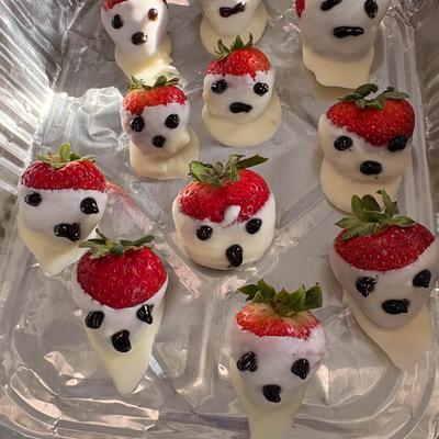 White chocolate-covered strawberries decorated with little ghost faces.