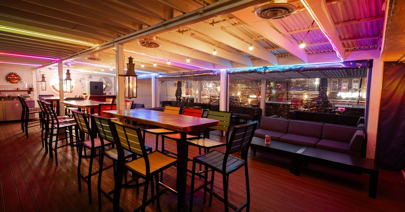 Interior, seating area, high seating community wooden top tables for eight, lounge in the back