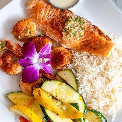 Seafood platter with grilled salmon, shrimp, scallops, rice, and sauteed vegetables.