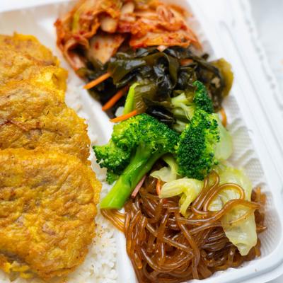 Korean Meat Ball  on rice, broccoli, glossy noodles, kimchi, and seaweed salad.