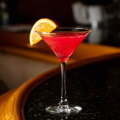 A glass of Rose cosmopolitan on bar counter.