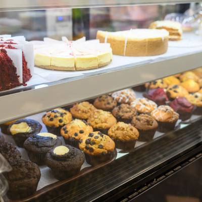 Display case features a variety of freshly baked muffins and cakes.