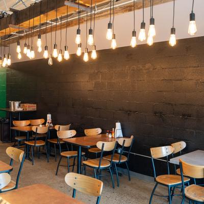 Dining area featuring distinctive hanging Edison bulbs against a dark wood-paneled wall.