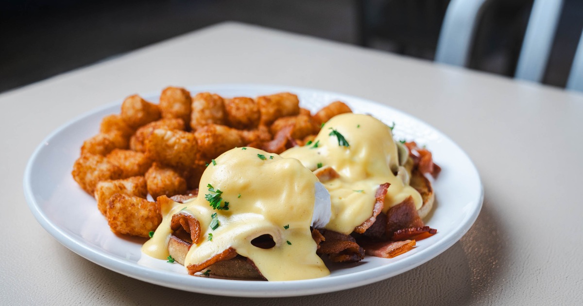 Bacon Eggs Benedict served with tater tots on the side