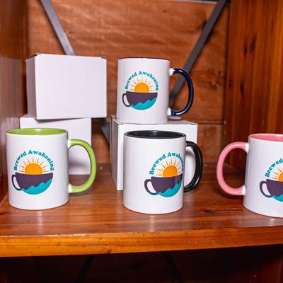 Brewed Awakening coffee mugs displayed on a wooden shelf.
