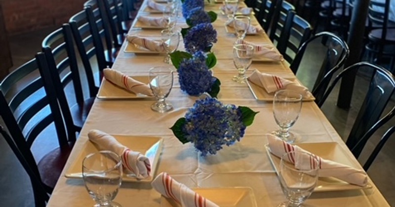 Nicely set dining table with flowers in the vases, ready for guests