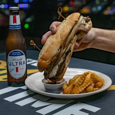 A hand dipping the Philly cheesesteak.