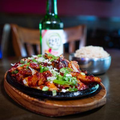 Spicy Pork Belly, rice and Korean wine in the background.