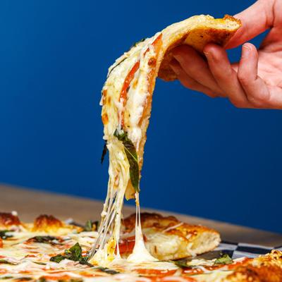 Hand lifting a slice of pizza from the tray.