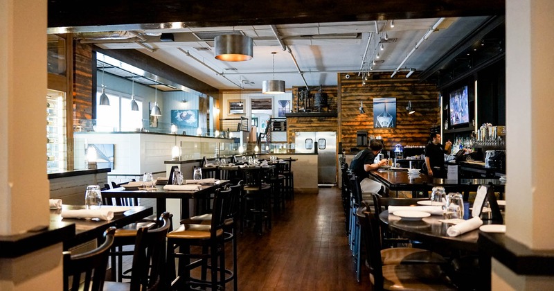 Interior, black high tables with tableware and black chairs, bar on the right