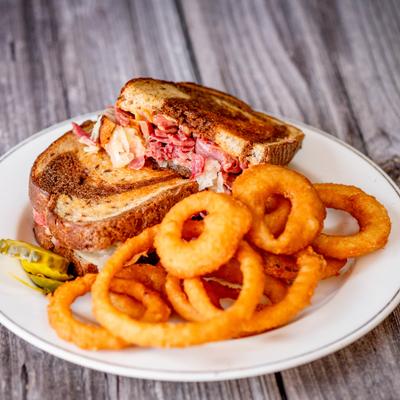 Reuben Sandwich with corned beef, sauerkraut, Swiss cheese and side of onion rings.