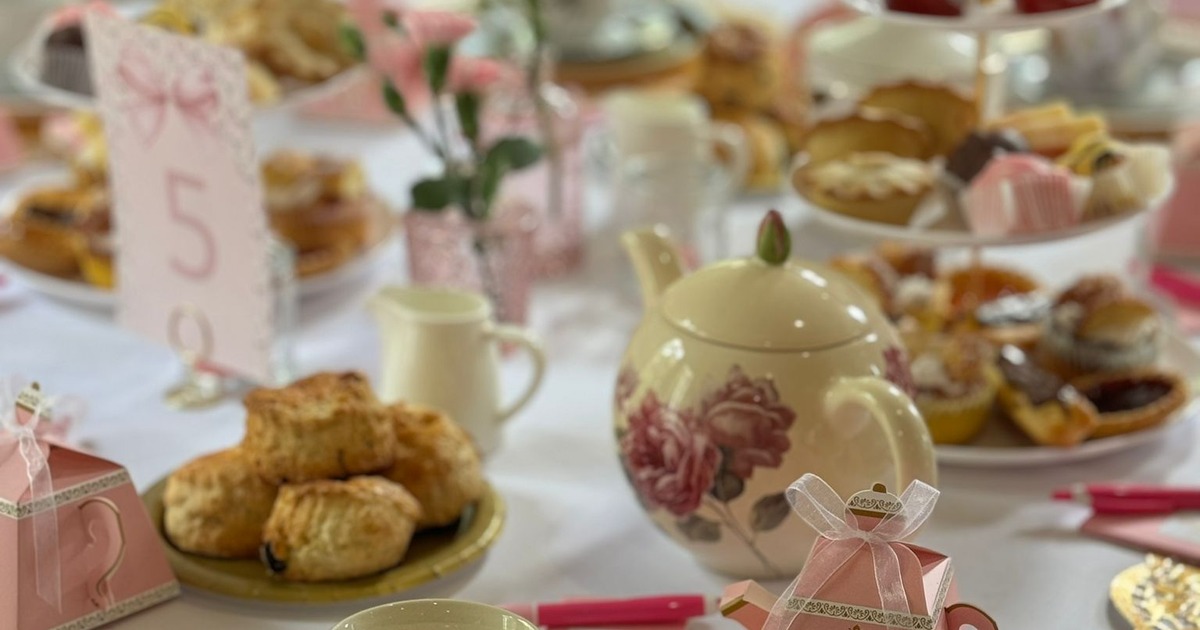 Afternoon tea setting with scones, pastries, and a rose-patterned teapot