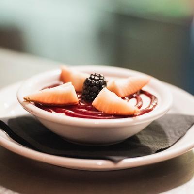 A dessert topped with berry sauce, strawberry slices, and a blackberry.