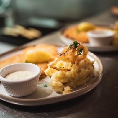 A plate of mashed potatoes topped with crispy onions, and a side of sauce.