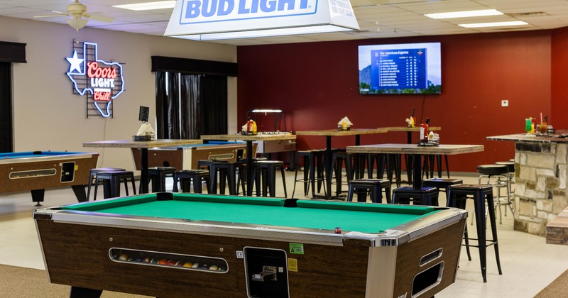 A recreational room with a pool table, "BUD LIGHT" sign and a "Coors Light Chill" neon sign