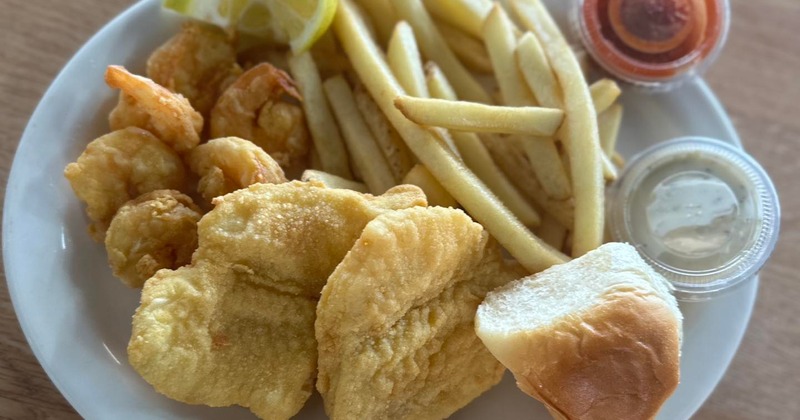 Fried fish and shrimp served with french fries, bread roll, tartar sauce and ketchup