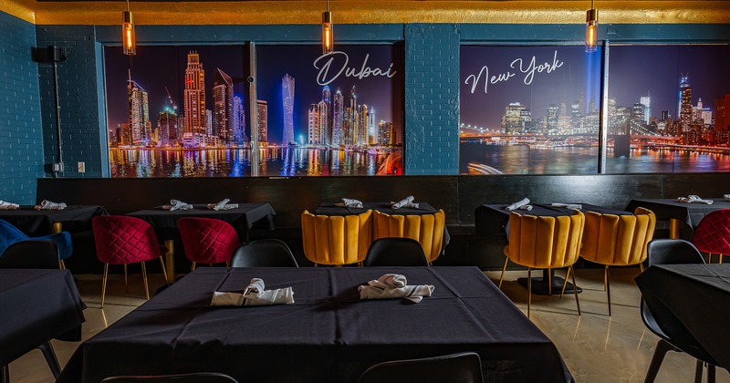 Interior, lined up tables with black tablecloths and upholstered chairs in different colors