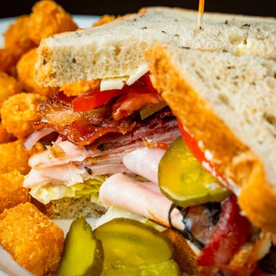 Chicken club sandwich with tater tots on the side.