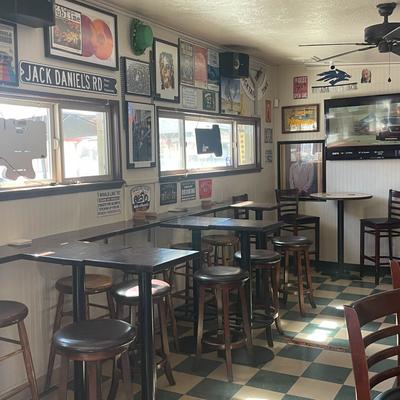 Interior, seating area with tables and bar stools, wall TV, stickers and framed pictures on walls.