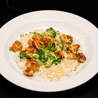 Grilled chicken bites with rice, broccoli, and scallions.