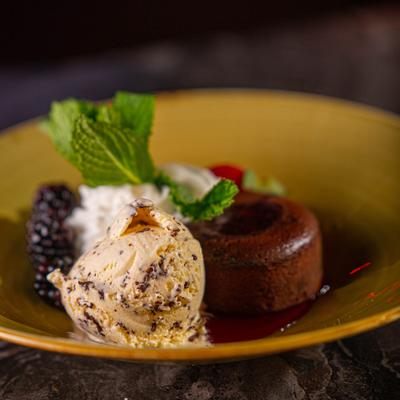 Chocolate souffle cake, sliced strawberry, whipped cream, ice cream and mint leaves