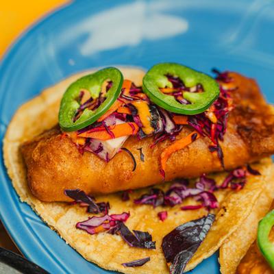 Open-faced cod taco topped with cabbage and jalapenos.