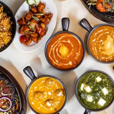 Overhead view of a variety of Indian dishes, spread on a white table.