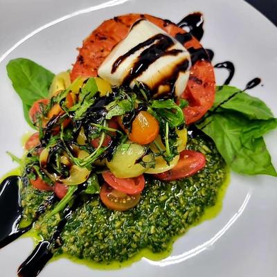 Grilled Caprese salad, with grilled tomato, burrata, pesto, arugula, cherry tomatoes, and balsamic