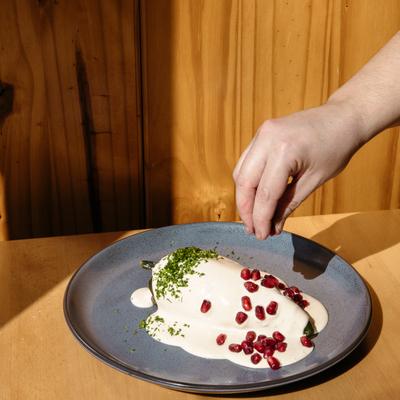 A hand topping a stuffed pepper with pomegranate seeds.