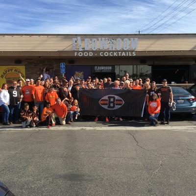 Exterior, lots of fans with a flag cheering in a parking lot